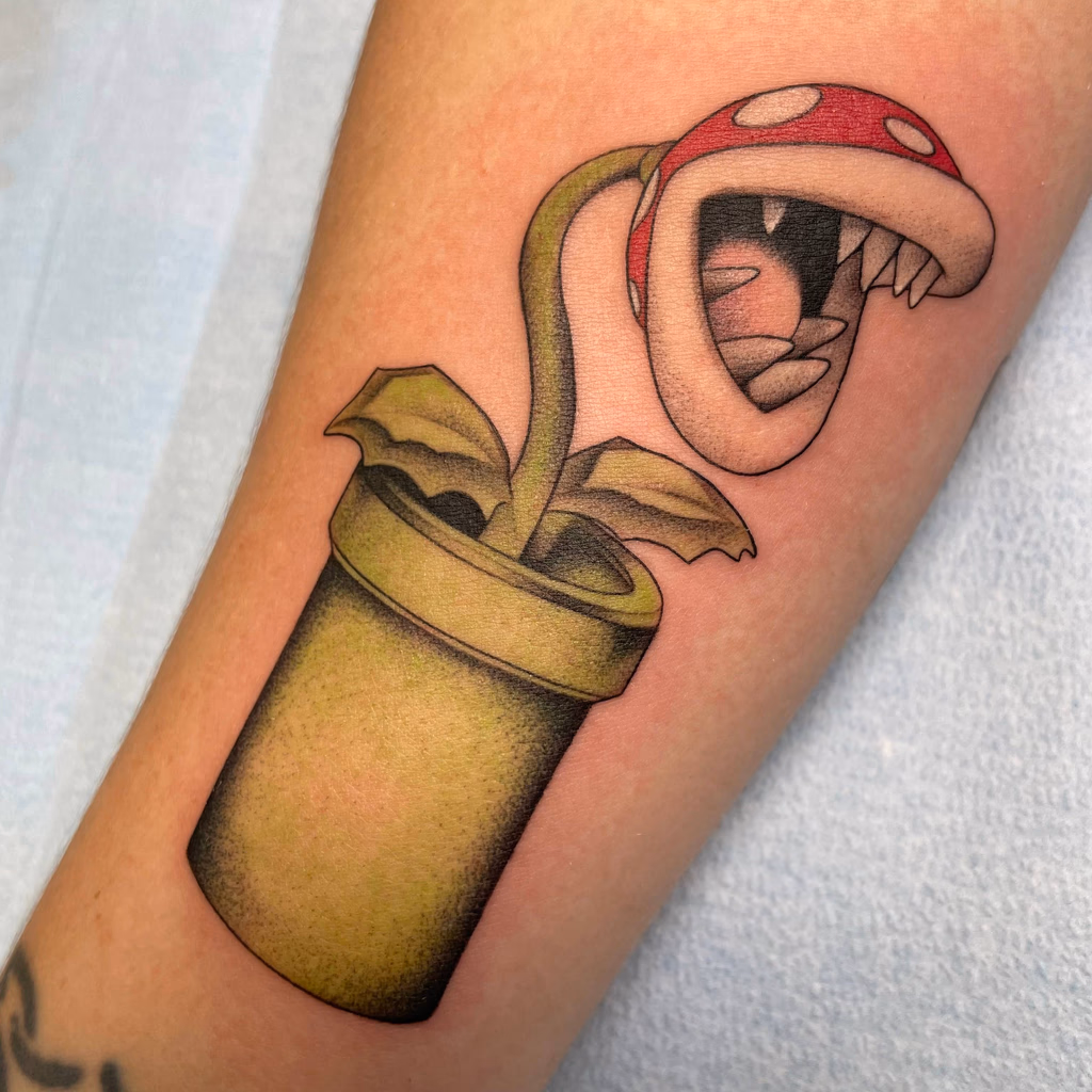 Colour tattoo of a green piranha plant in a pipe.