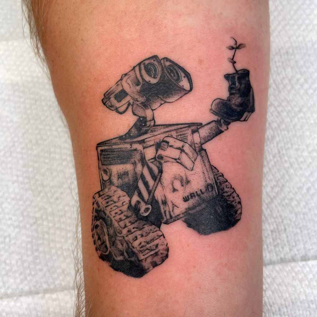 Black and grey illustrative tattoo of WALL-E holding a small plant.