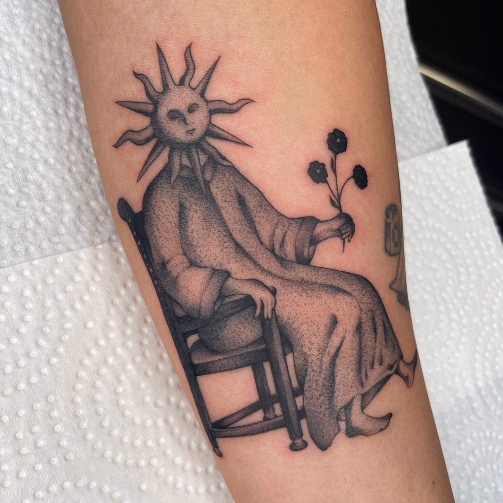 Black and grey illustrative tattoo of a seated figure with a sun-shaped head holding flowers.